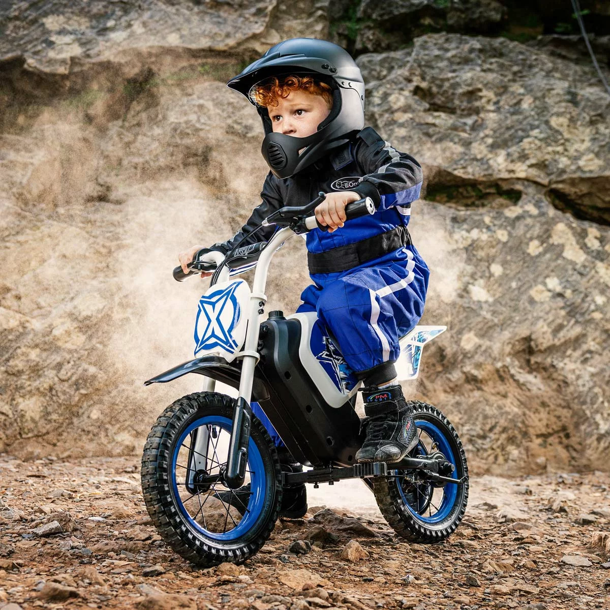 Black and red Xootz Cobolt 12V kids electric ride-on motorbike with 12-inch inflatable off-road tires parked on a dirt path.