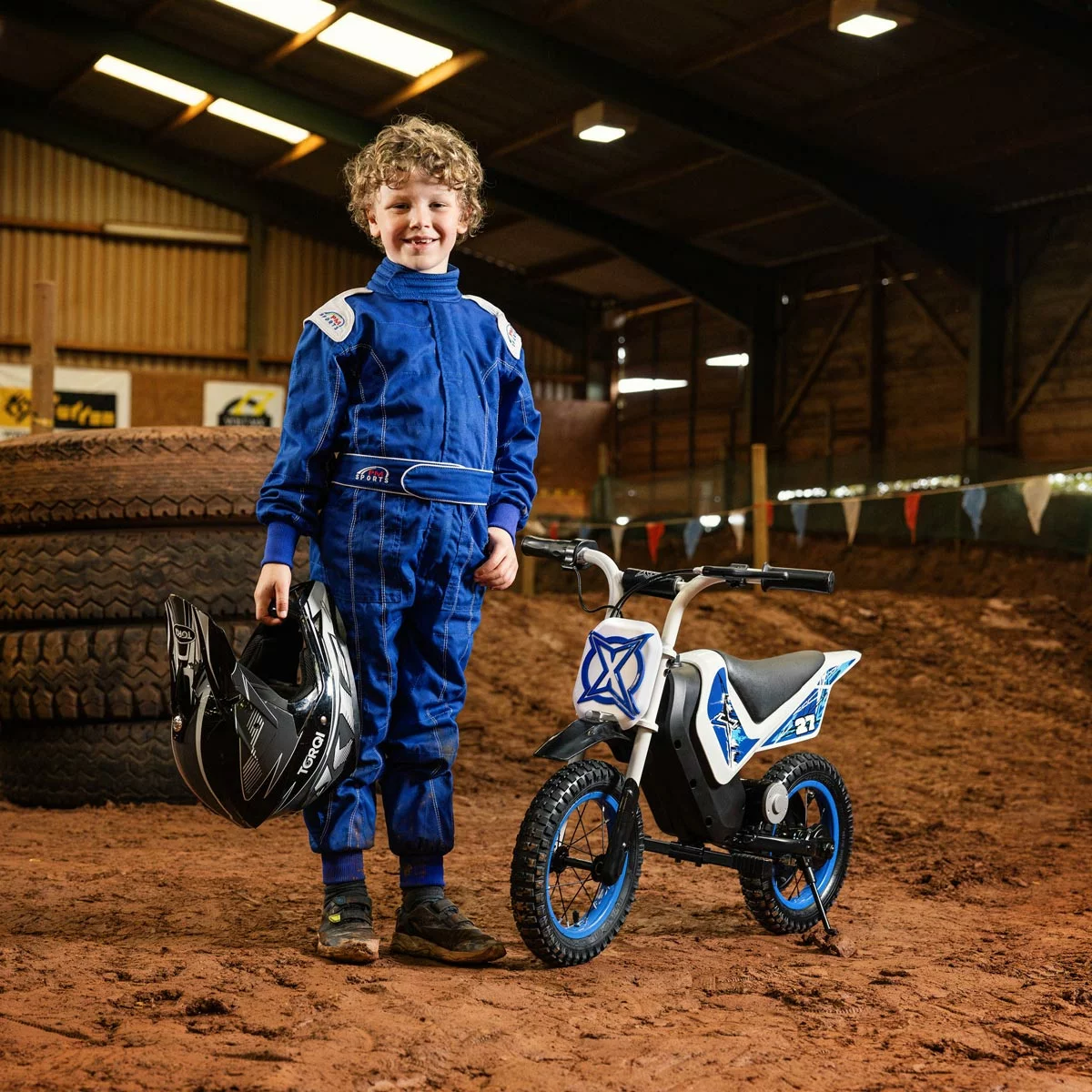 Black and red Xootz Cobolt 12V kids electric ride-on motorbike with 12-inch inflatable off-road tires parked on a dirt path.