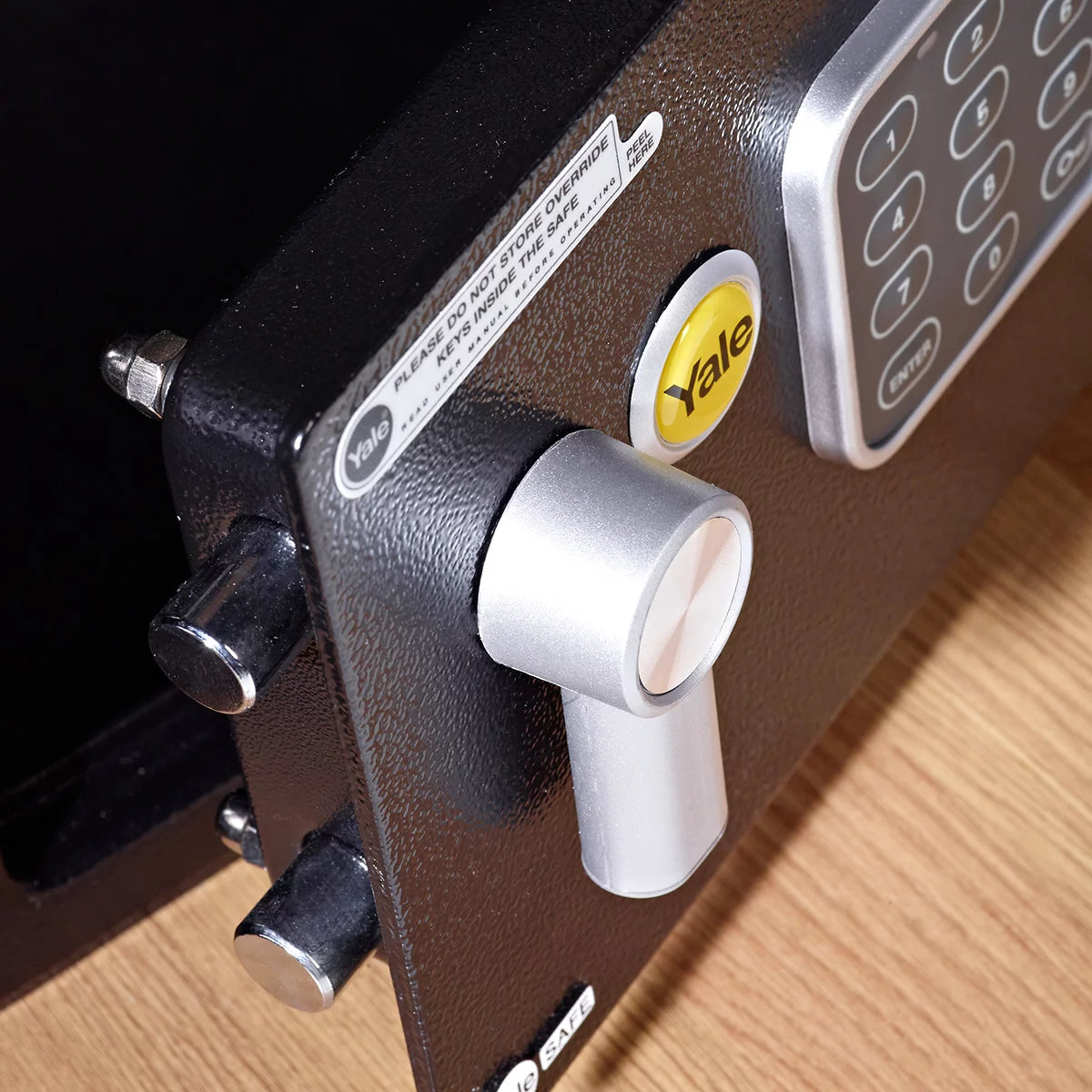 Front angle view of the black Yale 16.3L medium digital safe with electronic keypad and keyhole cover mounted on a light wood background.