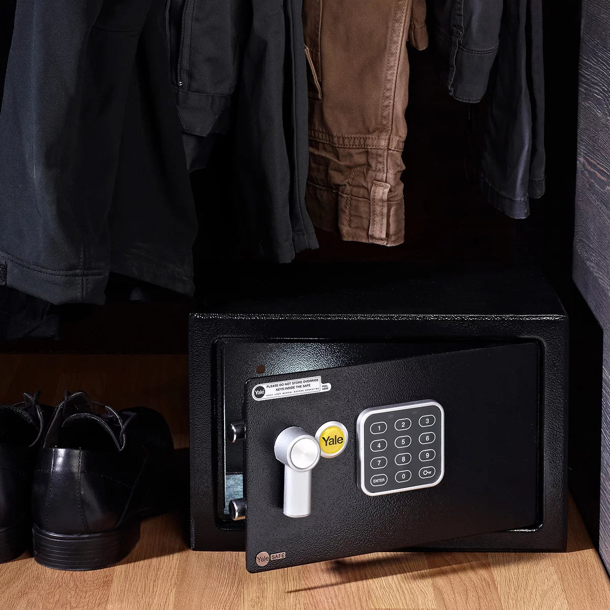 Front angle view of the black Yale 16.3L medium digital safe with electronic keypad and keyhole cover mounted on a light wood background.