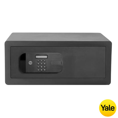A dark grey steel Yale premium high security motorised laptop safe with its digital LCD keypad lit up, sitting on a solid floor in a secure modern home office environment.