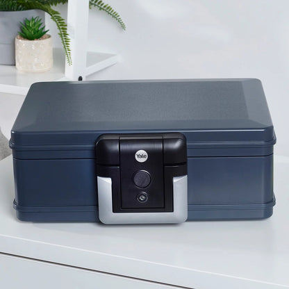 Front view of the black Yale 6.9L medium fire and waterproof chest safe with key lock and integrated handle sitting flat on a wooden surface.