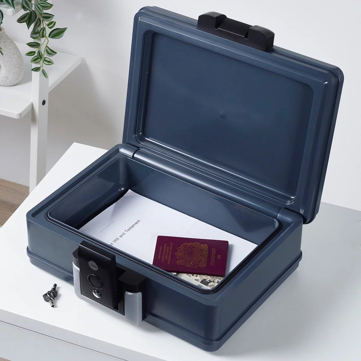 Front view of the black Yale 6.9L medium fire and waterproof chest safe with key lock and integrated handle sitting flat on a wooden surface.