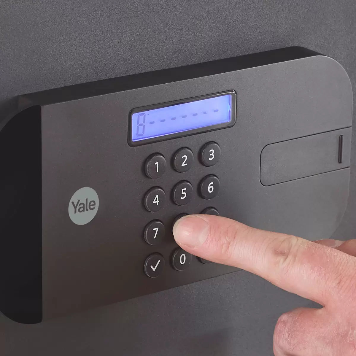 A side-profile view of the black Yale Premium Laptop Safe positioned on a desk, showcasing its slim profile, electronic keypad, and the heavy-duty motorised locking bolts visible on the edge of the open door.