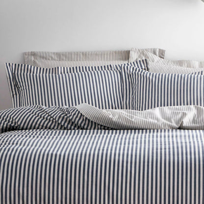 Reversible Yard Hebden navy blue and white striped cotton duvet cover neatly spread on a modern wooden bed frame within a brightly lit bedroom.