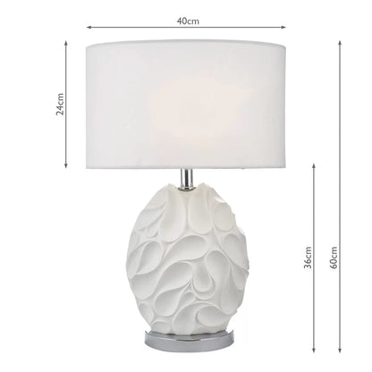 Front view of the matte white textured Zachary oval table lamp with undulating ridges, featuring a polished chrome neck and a white linen oval shade on a minimal concrete sideboard.