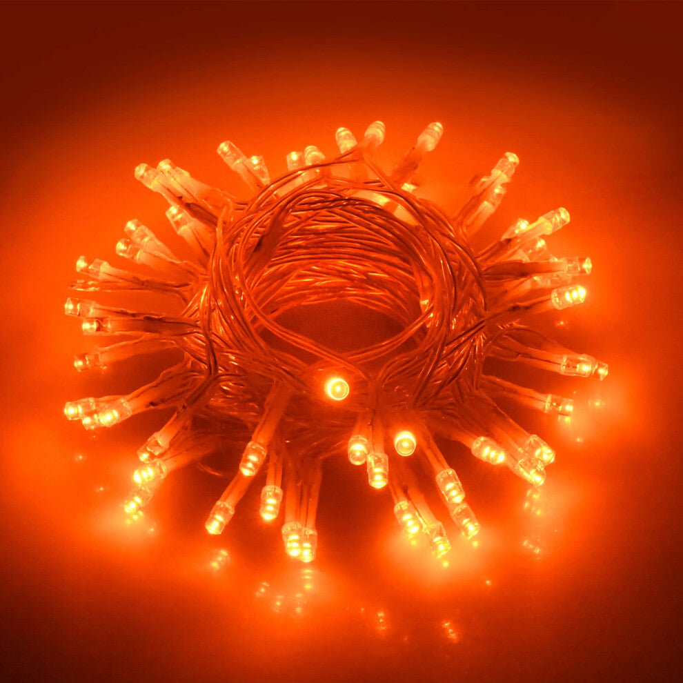 A 9.8ft strand of 30 orange LED fall fairy lights glowing brightly against an autumn-themed indoor wall backdrop.