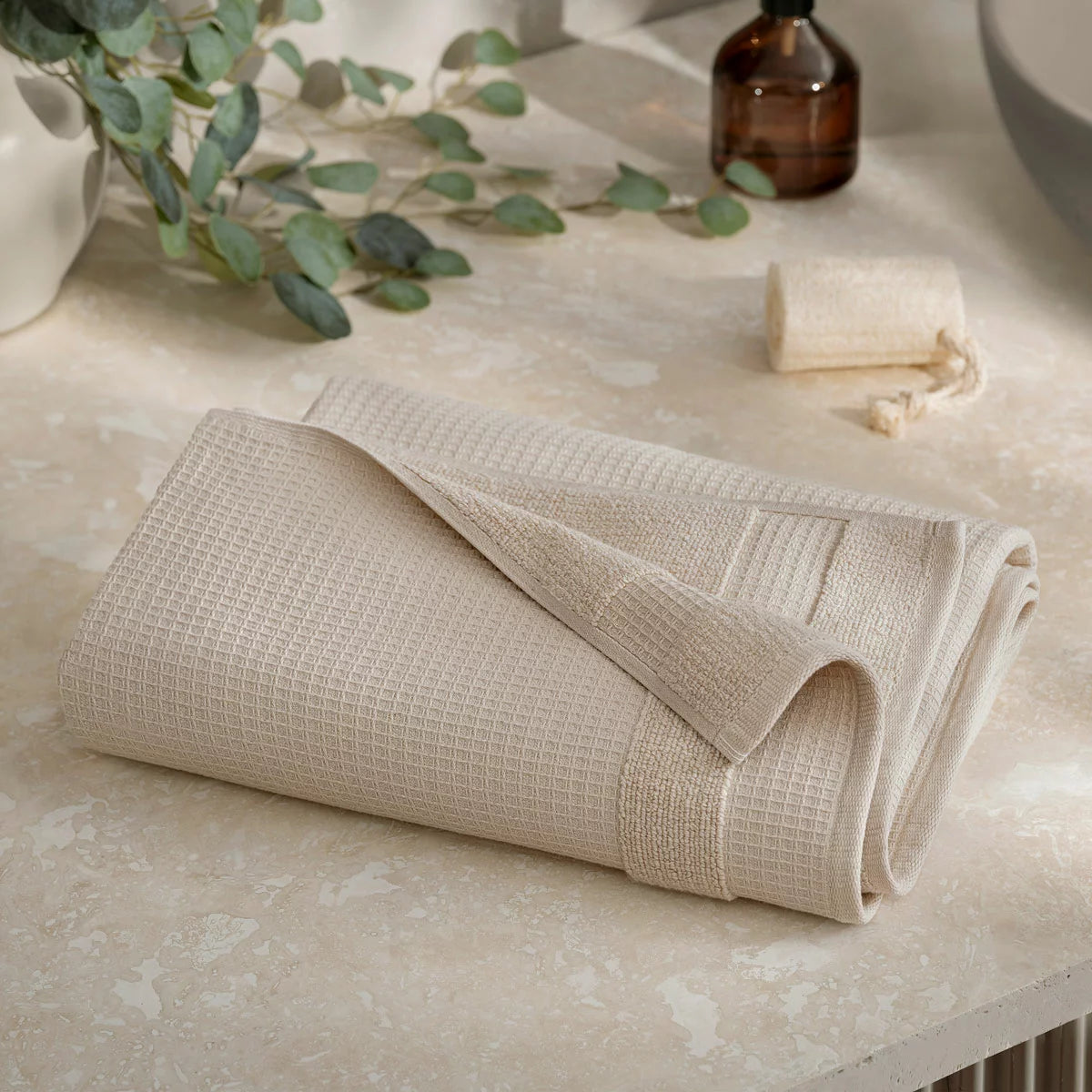 Close-up shot of the Welhome 100% cotton waffle-textured towel in grey, showing the terry backing on a modern bathroom wooden shelf.