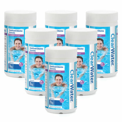 Six 1kg white tub containers of Clearwater stabilised chlorine granules grouped together on a grey stone patio beside a clear outdoor hot tub.