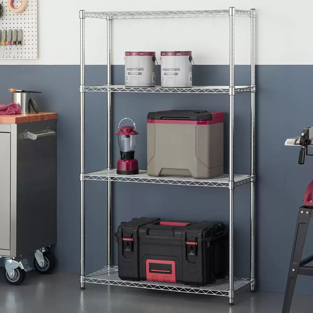 Three-quarter angle shot of the silver Trinity 4-tier chrome wire shelving unit standing empty against a bright, clean kitchen wall, highlighting its adjustable plastic sleeves and leveling feet.