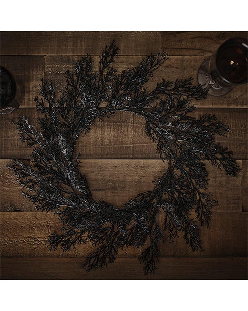 Flat lay view of four rectangular black foliage pattern placemats arranged neatly on a light oak wooden dining table.