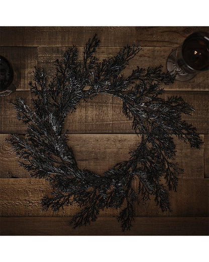 Flat lay view of four rectangular black foliage pattern placemats arranged neatly on a light oak wooden dining table.