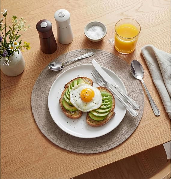 Top-down view of the silver polished Russell Hobbs Prague 24-piece cutlery set neatly arranged on a modern wooden dining table setting.