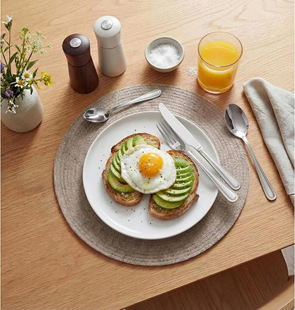 Top-down view of the silver polished Russell Hobbs Prague 24-piece cutlery set neatly arranged on a modern wooden dining table setting.
