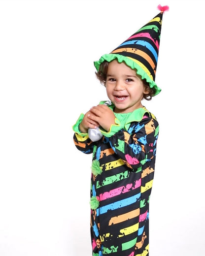 A child wearing a spooky Little Funhouse Clown jumpsuit and matching pointed clown hat standing in a Halloween setting.
